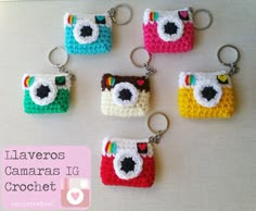 six crocheted camera keychains sitting on top of a white table next to each other