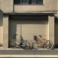 three bicycles parked next to each other in front of a garage door with shutters