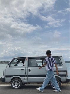 a man walking next to a van near the ocean