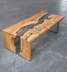 a bench made out of wood with metal legs on concrete flooring and walls in the background