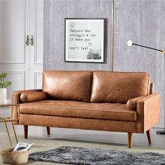 a brown leather couch sitting in a living room next to a lamp