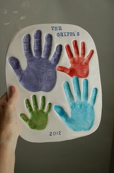 a person holding up a paper plate with handprints on it that says the grandpa's 2012