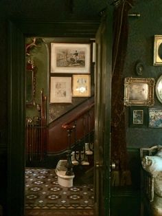 a hallway with pictures on the wall and stairs leading to another room that has an ornately decorated staircase