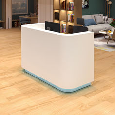 a white reception desk in an office with bookshelves and couches behind it