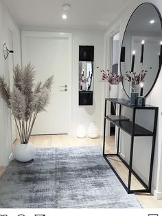 a room with a rug, mirror and vase on the floor in front of it