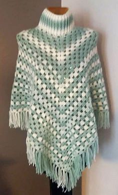 a green and white knitted ponchle with fringes