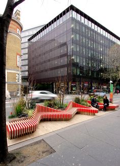 a group of benches sitting on the side of a road next to a tall building