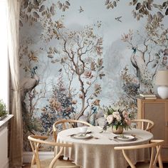 a dining room with a table and chairs in front of a wallpapered mural