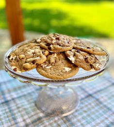 a glass cake plate filled with cookies on top of a blue and white table cloth