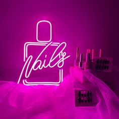 a neon sign that says nails on it in front of some lipstick and nail polish