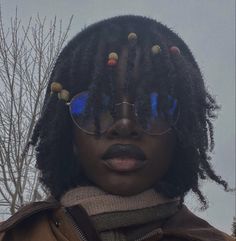 a woman with glasses and dreadlocks on her head is staring at the camera