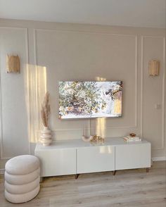 a living room with white furniture and large painting on the wall above it's entertainment center