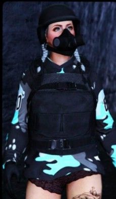 a woman wearing a black and blue camouflage outfit with a gas mask on her face