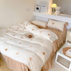 a bed with white sheets and teddy bears on the comforter is in a bedroom