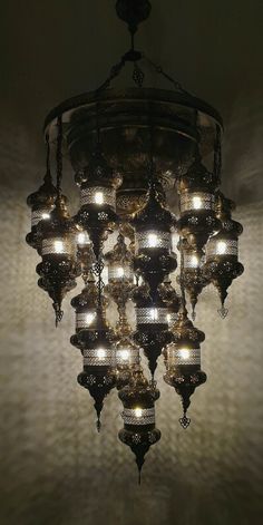 a chandelier hanging from the ceiling in a room with lights on and around it