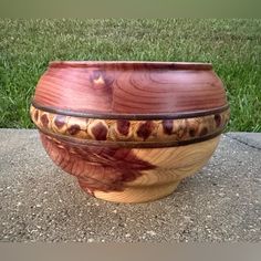 a large wooden bowl sitting on top of a cement slab in the grass next to a sidewalk