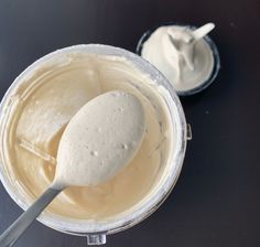 a spoon is in a bowl with some cream on the table next to another container