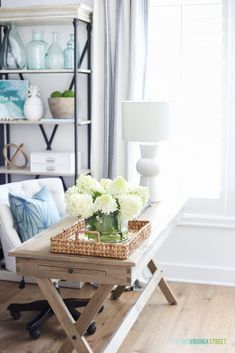 a living room with white furniture and flowers in a vase on the table next to it