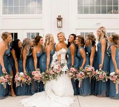 a group of women standing next to each other in front of a white building holding bouquets