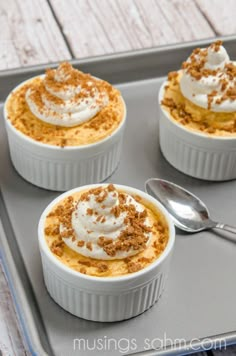 three desserts with whipped cream and cinnamon crumbs are on a baking tray