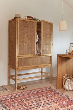 a wooden cabinet sitting next to a rug on top of a hard wood floor in front of a white wall