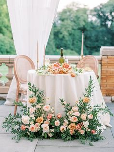 an outdoor table with flowers and greenery on it