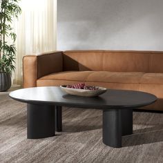 a brown leather couch sitting next to a table with a bowl on top of it