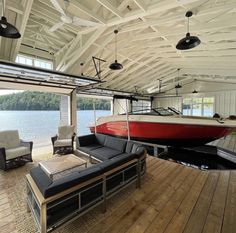 a boat is docked in the water next to a couch and chair on a wooden floor