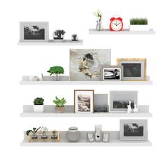 three white shelves with pictures, plants and other items on them in front of a clock