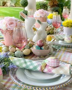 an easter table setting with pink and white flowers, eggs, napkins and bunny ears