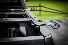 the front end of a black truck parked on top of a lush green field