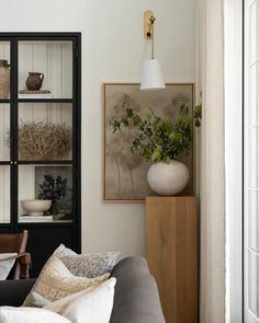 a living room filled with furniture and a white vase sitting on top of a table