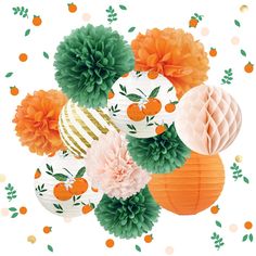 there are many paper flowers and decorations on the table with oranges, pom - poms