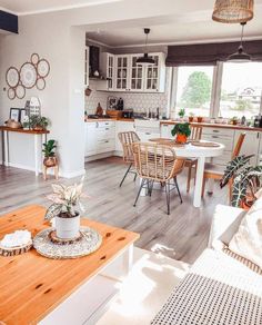 a kitchen and dining room with wood floors, white walls and furniture in the background