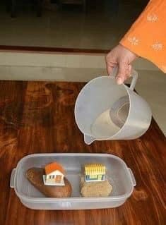 a person pouring something into a container on top of a wooden table with other items in it