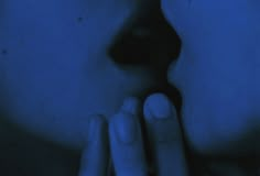 a woman's face is illuminated by the blue light from her hand to her mouth