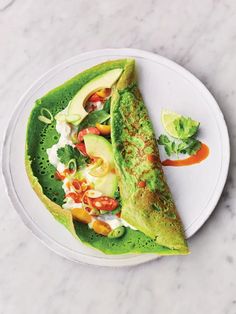 a white plate topped with an omelet covered in lettuce