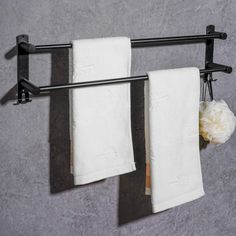 two white towels hanging on a towel rack with black metal bars and flowers in vases