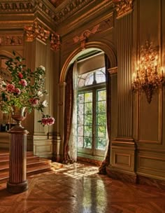 an ornate room with large windows and flowers in vases on the floor next to stairs