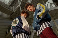 two young men standing next to each other in front of a building with spiral staircases