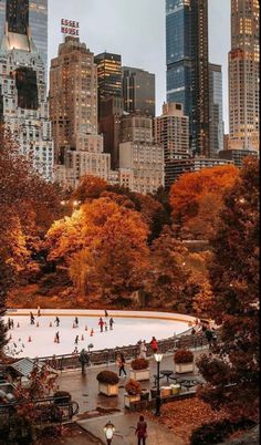 an ice rink surrounded by tall buildings in the middle of a city with people skating on it