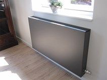 a radiator in the corner of a room next to a window with a potted plant on it