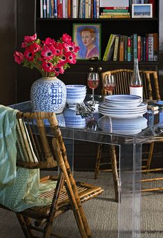 a dining room table with plates and glasses on it, surrounded by bookshelves