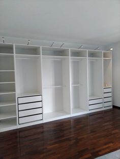 an empty room with white shelving and wood flooring in the middle of it