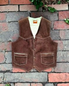 a brown suede vest hanging on a brick wall