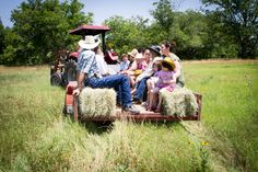 a group of people riding on the back of a truck filled with hay in a field