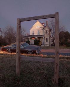 an old car is parked in front of a house with a wooden frame on the grass