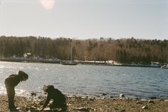 two people are on the beach by some water