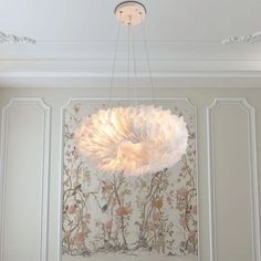 a white chandelier hanging from the ceiling in a room with floral wallpaper