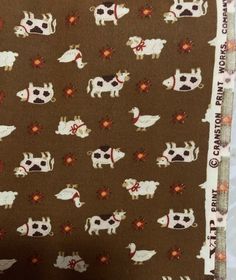 the fabric is brown with cows and flowers on it